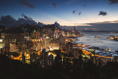 High angle view of illuminated city by sea against sky