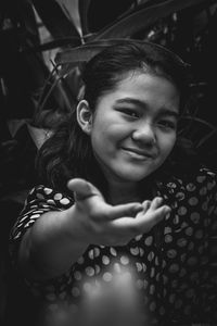 Selective focused portrait of a girl wearing a polkadot dress reaching out her hand to the camera 