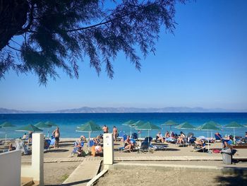 People on beach against blue sky