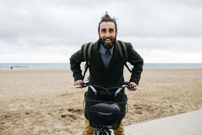 Portrait of happy man with e-bike at the beach