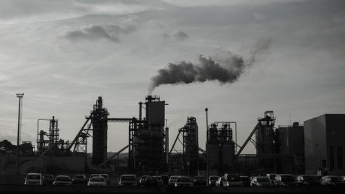 Smoke emitting from factory against sky