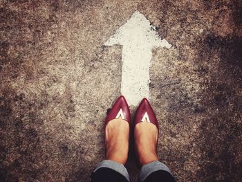 Low section of woman standing on arrow symbol