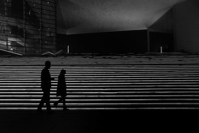 Silhouette man and woman walking on steps at night