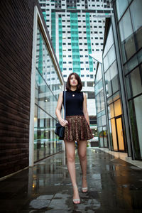 Full length portrait of woman standing against building