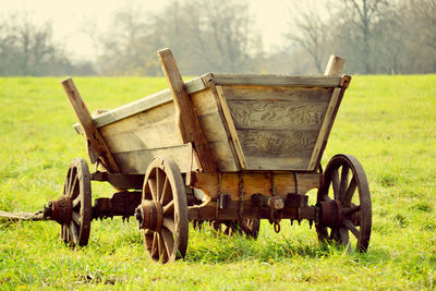 Old wooden cart on the field with green grass in the summer, the filter