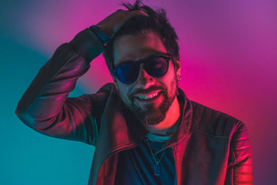 Portrait of young man wearing sunglasses against gray background