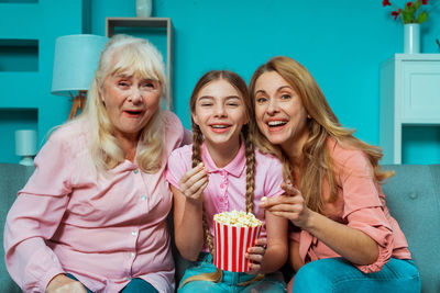 Cheerful family watching movie while eating popcorn at home