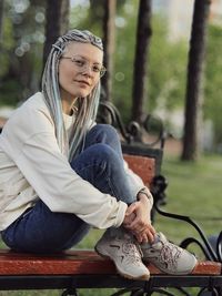 Portrait of young woman using mobile phone while sitting outdoors