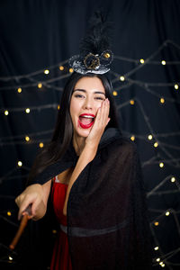 Portrait of beautiful woman standing against illuminated lighting equipment