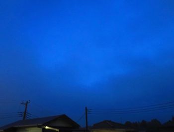 Low angle view of silhouette house against blue sky