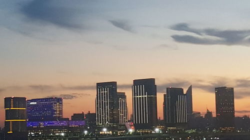 Illuminated cityscape against cloudy sky