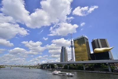 Modern buildings by river against sky in city