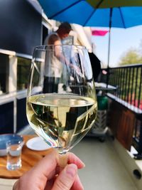 Cropped image of hand holding wineglass on balcony