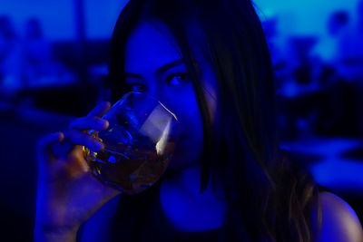 Close-up portrait of a young woman drinking glass