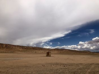 Dramatic sky over sand and public restroom