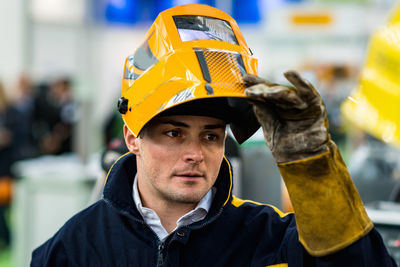 Man looking away while holding helmet at workshop