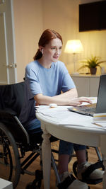 Woman using phone while sitting on table