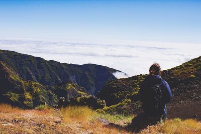 Rear view of woman standing on mountain against sky