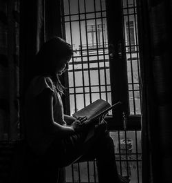 Side view of young woman reading book at home