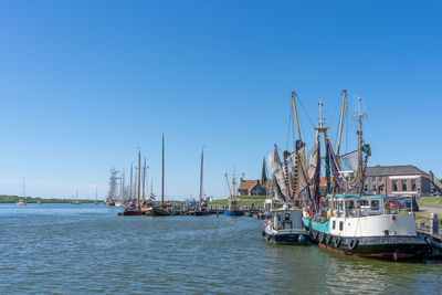 Sailboats moored in sea against clear blue sky