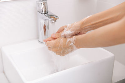 Cropped hand washing hands in sink