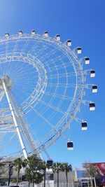 Low angle view of ferris wheel against clear blue sky