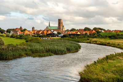 Scenic view of river by buildings against sky