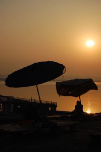 Silhouette beach against sky during sunset