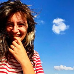 Low angle portrait of smiling woman against sky