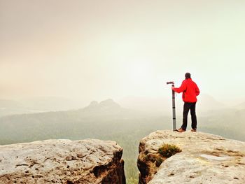 Rear view of man standing on rocks against mountain