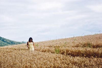 Woman walking on field against sky