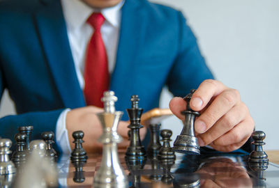 Midsection of businessman playing chess in office