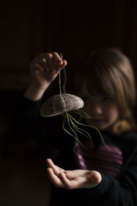 Girl playing with air plant hanging from sea urchin in darkroom