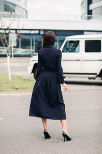 Rear view of woman with umbrella walking in city