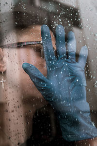 Person seen through wet glass window during rainy season