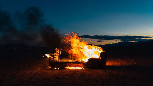 Bonfire on wooden structure in field against sky at night