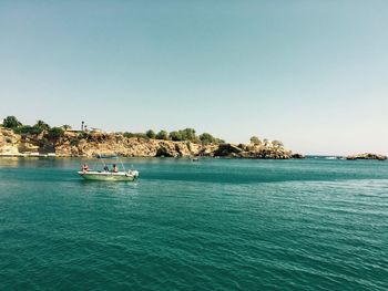 Boat sailing in sea against clear blue sky