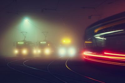 Light trails on illuminated train against sky at night