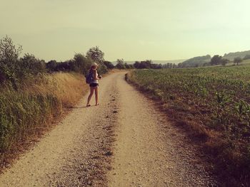 Rear view of woman walking on field against sky