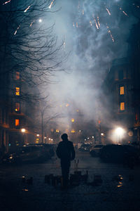 Rear view of man standing on street at night