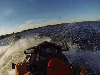 Close-up of man photographing sea against sky