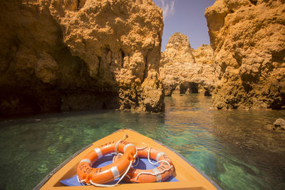 Cropped image of boat with life belts on sea amidst cliffs