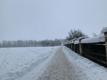 Snow covered field against sky during winter