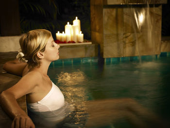 Woman with eyes closed in swimming pool at night