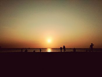 Silhouette of people on beach at sunset