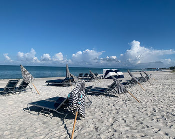 Deck chairs on beach against blue sky