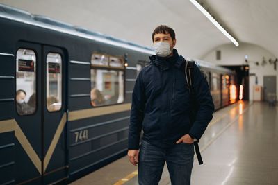 Man wearing mask standing on railroad station platform