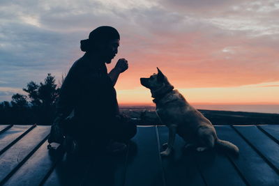 Side view of man with dog sitting on roof