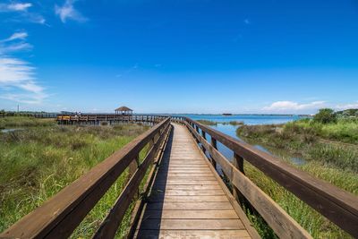 Footbridge over sea against blue sky