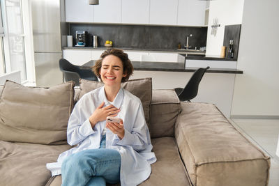 Young woman using laptop while sitting on sofa at home